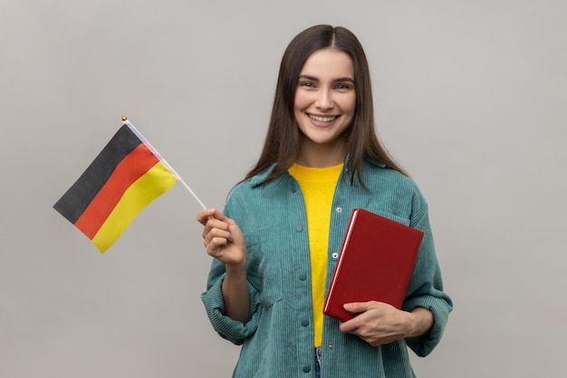 Optimistic woman holding in hands book and german flag education courses abroad _ Premium Photo